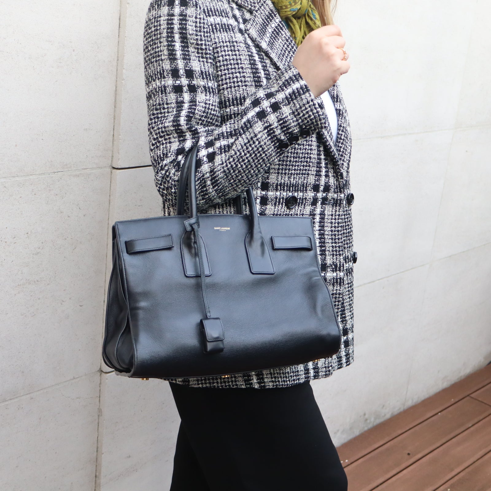 Femme portant le Sac du Jour YSL noir en cuir à la main, style chic et minimaliste